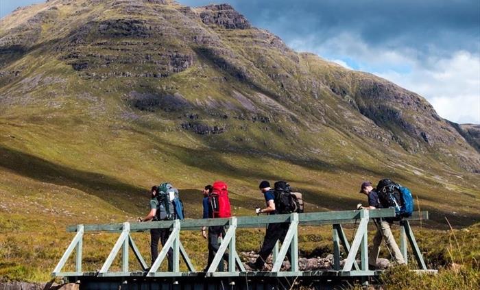 bearded men adventures, 4 men walk across a bridge in the mountains